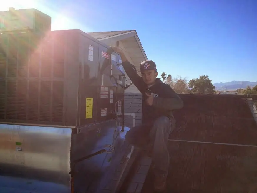 HVAC technician performing Air Duct Cleaning on a rooftop unit in Huntington Beach