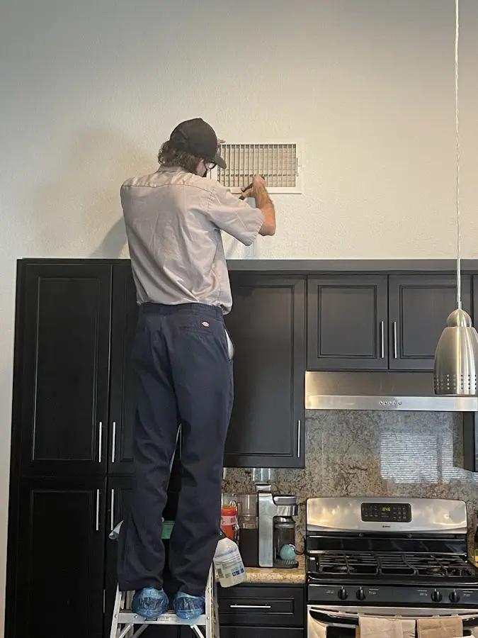 Technician inspecting an air vent during HVAC service in Huntington Beach